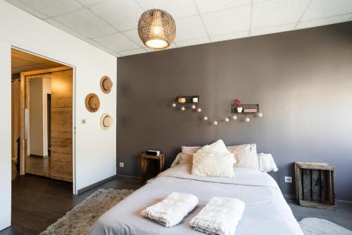 una camera da letto con un grande letto con lenzuola e cuscini bianchi di Charmant logement Villefranche a Villefranche-sur-Saône