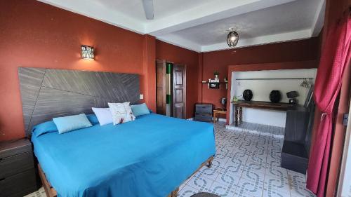 een slaapkamer met een blauw bed en rode muren bij Villa frente al mar en Yelapa para 4 personas in Yelapa