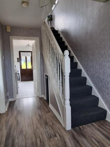 a hallway with a staircase in a home with wood floors at Private room City skyline and mountain views close too belfast centre and airports free parking in Belfast