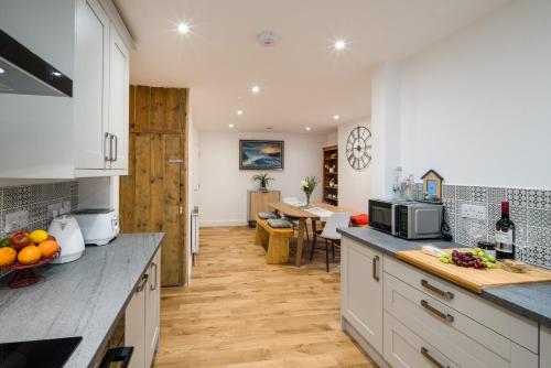 a kitchen with white cabinets and a dining room with a table at 3 Anzac Cottage in Cowes