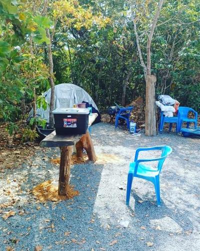 una parrilla en un tocón con una silla y una tienda de campaña en Camping e Balneário Rio dos Bugres en Porcas