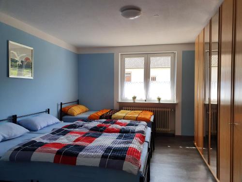 two beds in a bedroom with blue walls and windows at Ferienwohnung Paul in Losheim