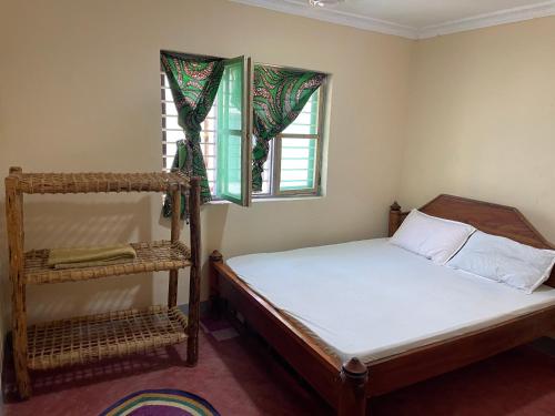 um pequeno quarto com uma cama e uma janela em Afrobukuu house em Paje