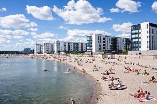 um grupo de pessoas numa praia com edifícios em Lovely apartment near the Beach em Helsinque