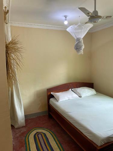 Afrobukuu house في باجي: غرفة نوم بسرير ومروحة سقف