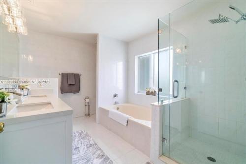 a bathroom with a glass shower and a sink at Kendall Vacation Luxury Home in Miami