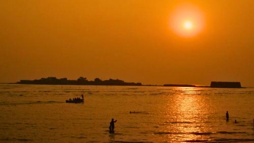 a group of people in the water at sunset at Awaara Backpackers Hostel, Alibag in Alibag