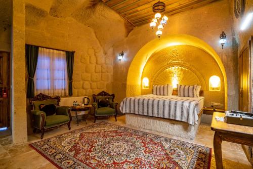 a bedroom with a bed and chairs in a room at CAPPANAR CAVE HOTEL in Nar