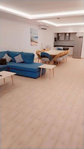 ein Wohnzimmer mit einem blauen Sofa und Tischen in der Unterkunft Miami Paradise only family للعوايل فقط in Durrat Al-Arus