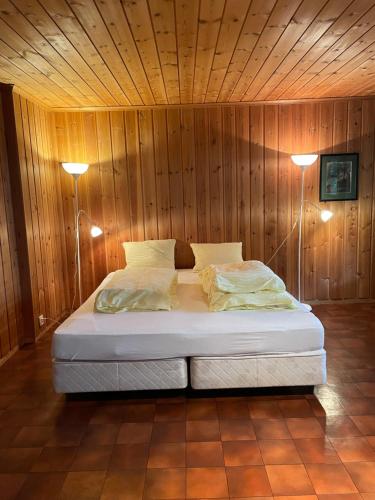 uma cama num quarto de madeira com duas luzes em Espes residens em Jordal