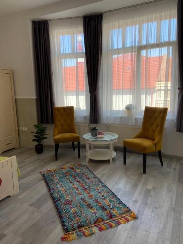 a living room with two chairs and a table and a rug at Penzión Bihari in Dunajská Streda