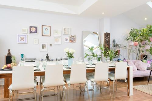 a dining room with a table and white chairs at Luxury 6 Double Bedroom London Town house in Ealing