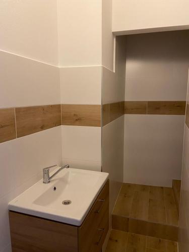 ein Badezimmer mit einem weißen Waschbecken und Holzschränken in der Unterkunft Penzión Bihari in Dunajská Streda