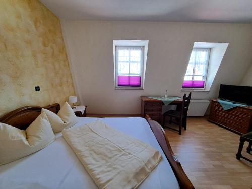 a bedroom with a bed and a table and windows at Hotel zum Hirsch in Lucka