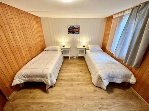 two beds in a room with two tables and a window at Staubbach View - Traditional Chalet Apartment in Lauterbrunnen