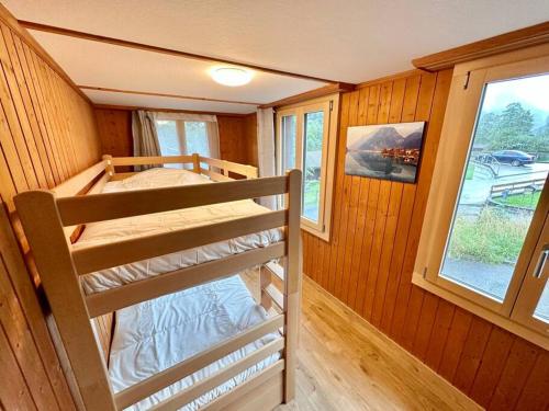 two bunk beds in a room with a window at Staubbach View - Traditional Chalet Apartment in Lauterbrunnen