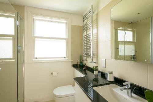 a bathroom with a sink and a toilet and a mirror at Luxury 6 Double Bedroom London Town house in Ealing