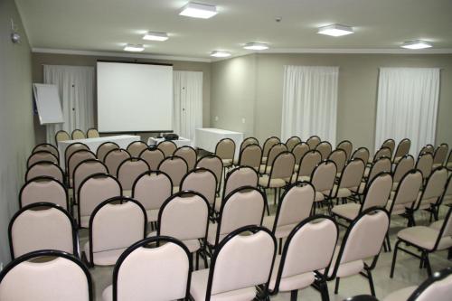 a conference room with chairs and a white screen at Hotel Horto in Rondonópolis