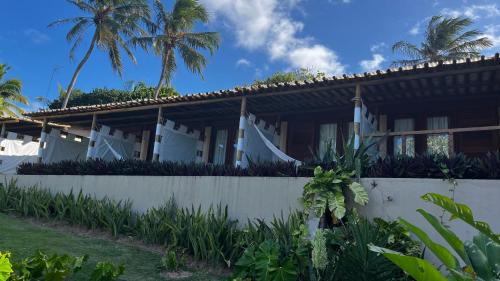 a house with a white fence and palm trees at Hotel da Pipa in Pipa