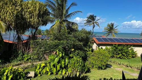 a house with a solar roof with the ocean in the background at Hotel da Pipa in Pipa