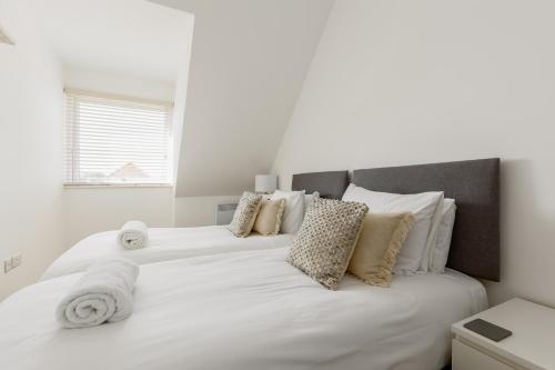 1 dormitorio con 2 camas con sábanas y almohadas blancas en 2 bed Seaside Apartment with Parking, en Southbourne
