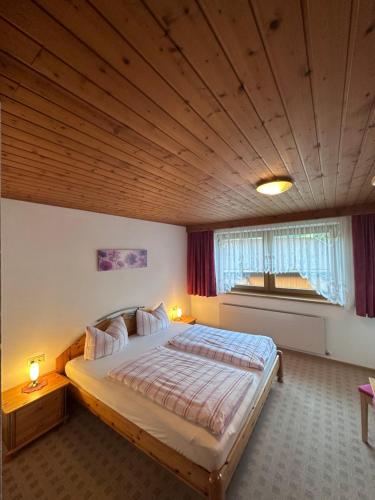 a bedroom with a large bed with a wooden ceiling at Haus Claudia in Schwendau