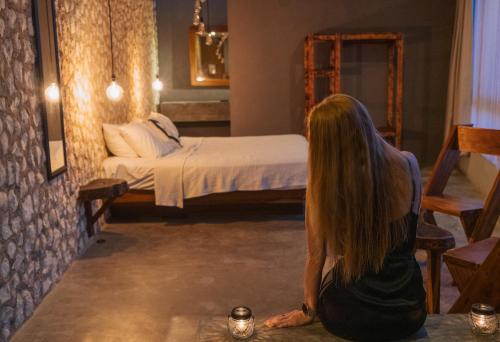 a woman sitting on the floor in a room with a bed at BAU Tulum in Tulum