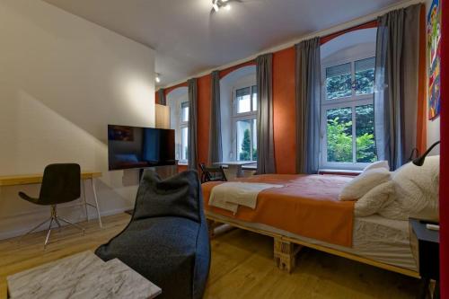 a bedroom with a bed and a tv and windows at Wohnung 3 neben Warschauer Platz und Spree in Berlin
