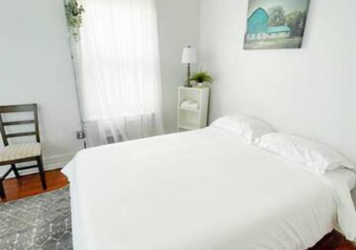 a white bedroom with a bed and a chair at Legacy - Spring Garden University City in Philadelphia
