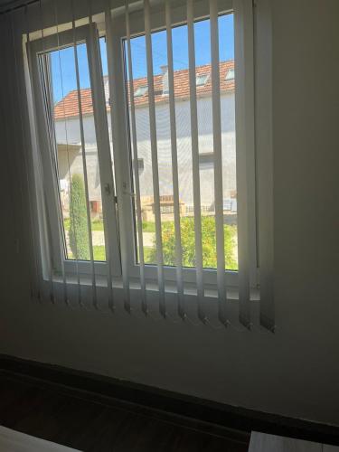 a window with white blinds and a view of a yard at Sobe Šponga 4, in Kikinda