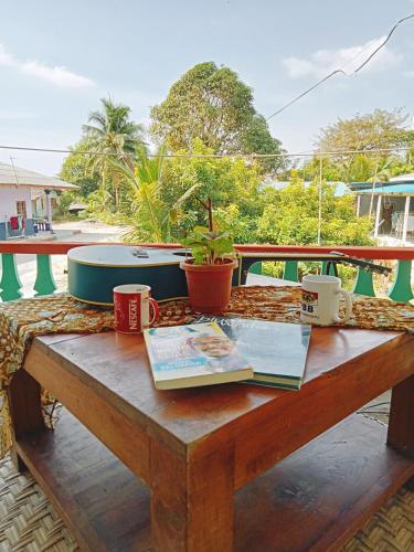 un tavolo in legno con due tazze di caffè e un libro di Captain J's Boutique Crib a Kampong Pandan