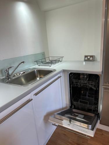 a kitchen with a sink and an open dishwasher at City Centre 3 bedrooms apartment with parking in Nottingham