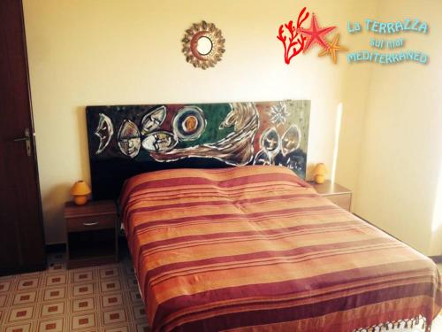 1 dormitorio con 1 cama con una pintura en la pared en La Terrazza Sul Mar Mediterraneo, en Marinella di Selinunte
