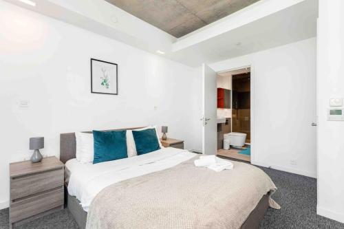 1 dormitorio blanco con 1 cama grande con almohadas azules en Luxury Apt 3min walk to London Excel,City Hall, O2, en Londres