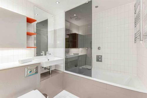 baño blanco con ducha y lavamanos en Luxury Apt 3min walk to London Excel,City Hall, O2, en Londres