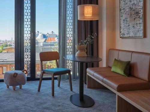 a living room with a couch and a table and a chair at Adina Apartment Hotel Munich in Munich