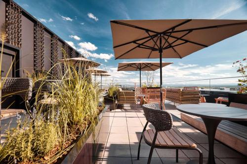 a patio with tables and chairs and an umbrella at Adina Apartment Hotel Munich in Munich