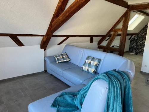 a blue couch in a living room with wooden ceilings at Gîte Familie 
