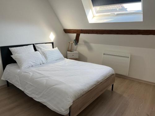 a bedroom with a bed with white sheets and a skylight at Gîte Familie in Meyenheim