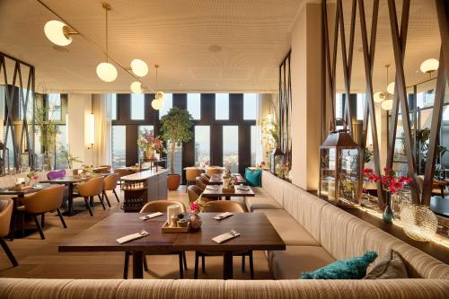 a restaurant with tables and chairs and windows at Adina Apartment Hotel Munich in Munich