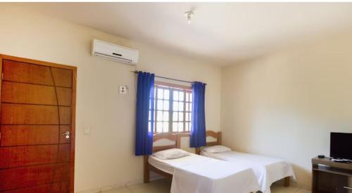 sypialnia z 2 łóżkami i oknem z niebieskimi zasłonami w obiekcie hotelCoxipóoyo w mieście Cuiabá