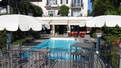a swimming pool with umbrellas and chairs and a table and a swimming pool at Hotel Belvedere Ranco in Ranco