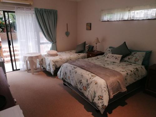 um quarto com 2 camas e uma janela em Clivia Guesthouse em Pietermaritzburg