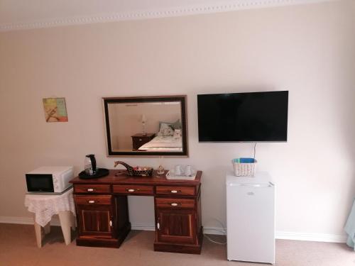 a room with a desk with a television and a microwave at Clivia Guesthouse in Pietermaritzburg