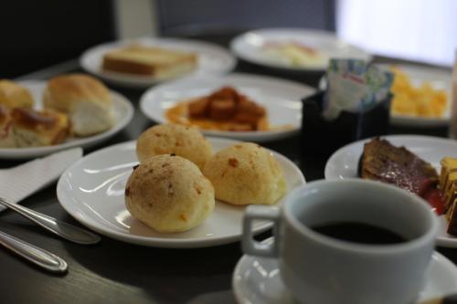 a table with plates of food and a cup of coffee at Stop Inn Antonio Carlos in Belo Horizonte