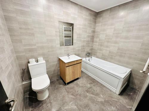 een badkamer met een bad, een toilet en een wastafel bij Confort City Residence in Popeşti-Leordeni