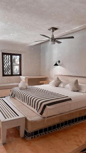 a bedroom with a large bed with a ceiling fan at La Conchita Tulum in Tulum