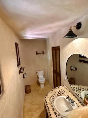 a bathroom with a sink and a mirror and a toilet at La Conchita Tulum in Tulum