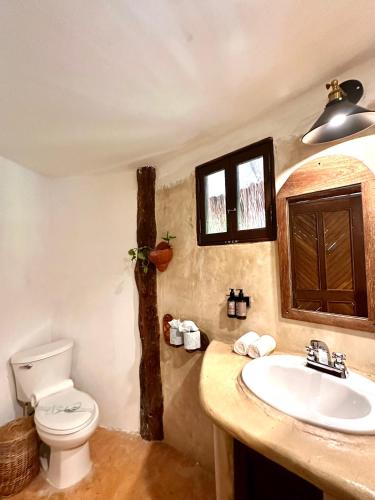 a bathroom with a white toilet and a sink at La Conchita Tulum in Tulum