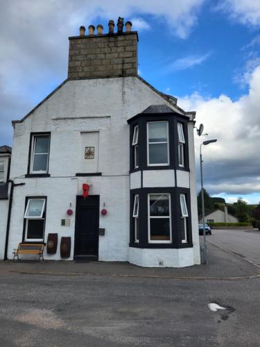 a white and black building with a roof at Macbeth Arms in Lumphanan